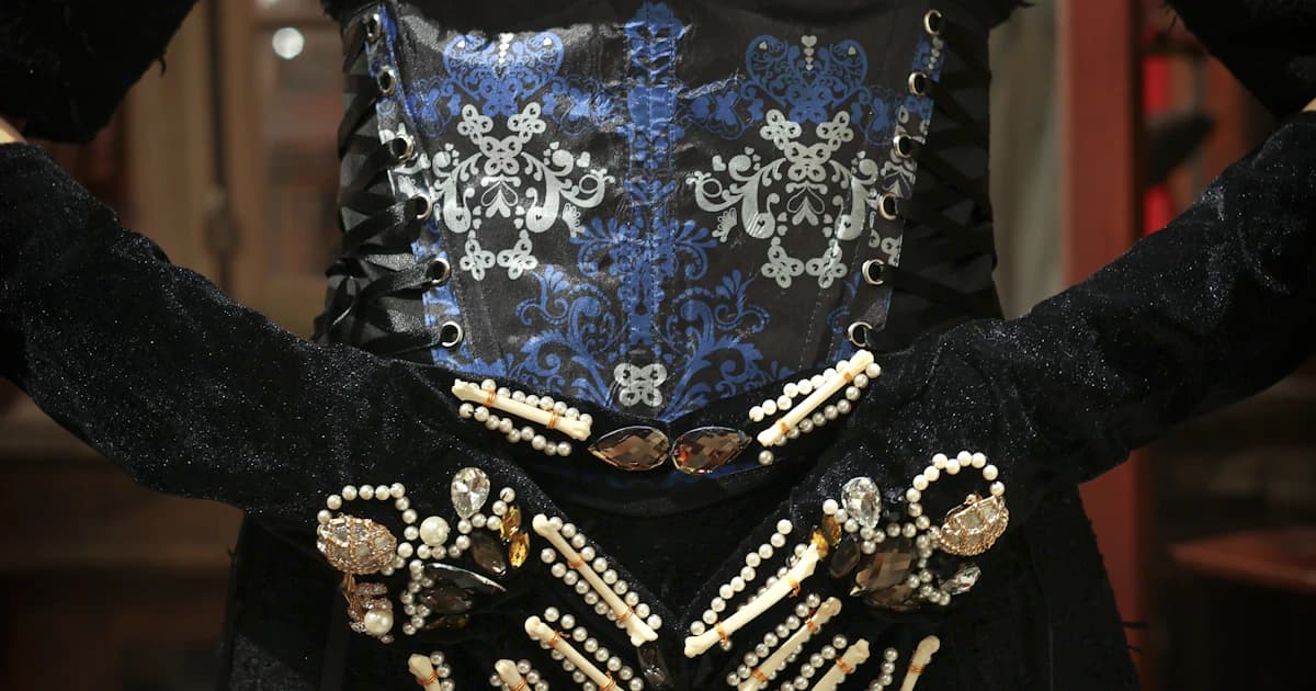 A detailed blue and black garment displayed on a mannequin