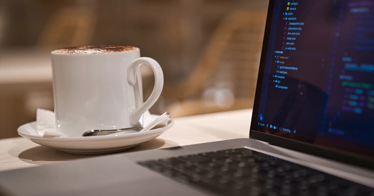 A laptop and coffee cup on a work table