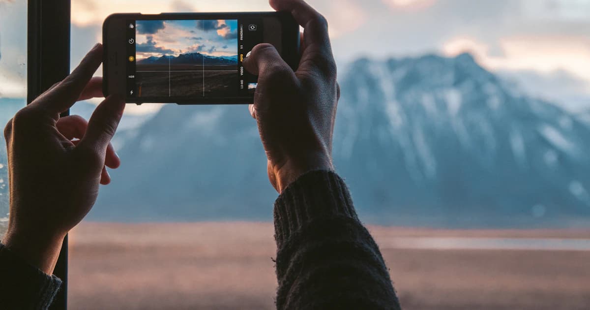 A smartphone photographing mountains beside a lake