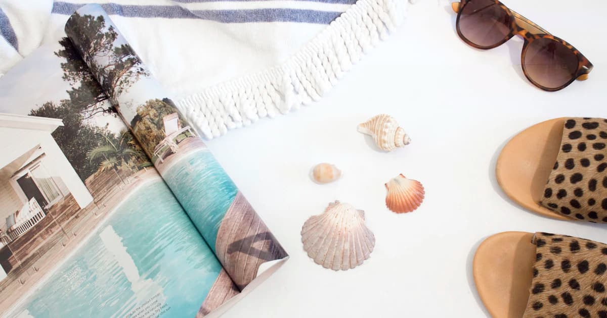 Summer accessories and a magazine arranged on a white surface