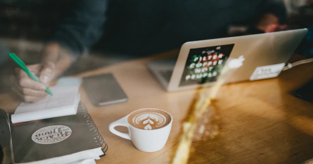 A laptop and coffee cup on a wooden cafe table