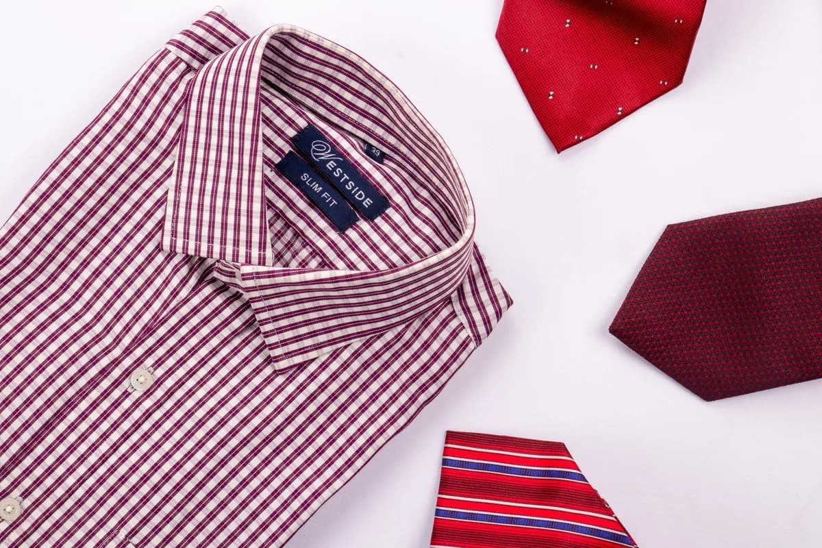Red gingham shirt folded flat beside three ties