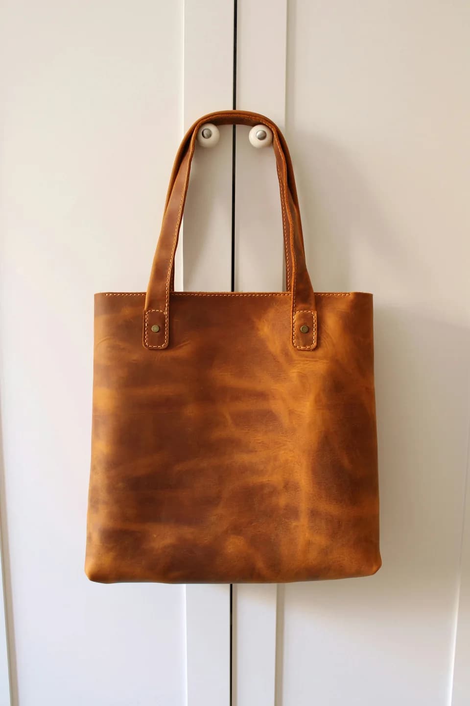 Original leather tote hanging against a white wall